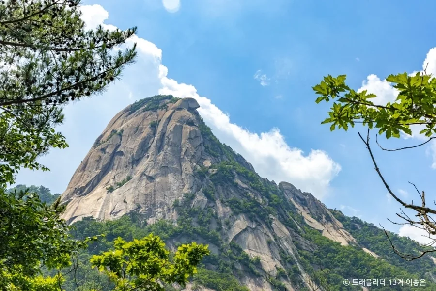 Bare granite dome at the top of Bukhansan seen through trees from below
